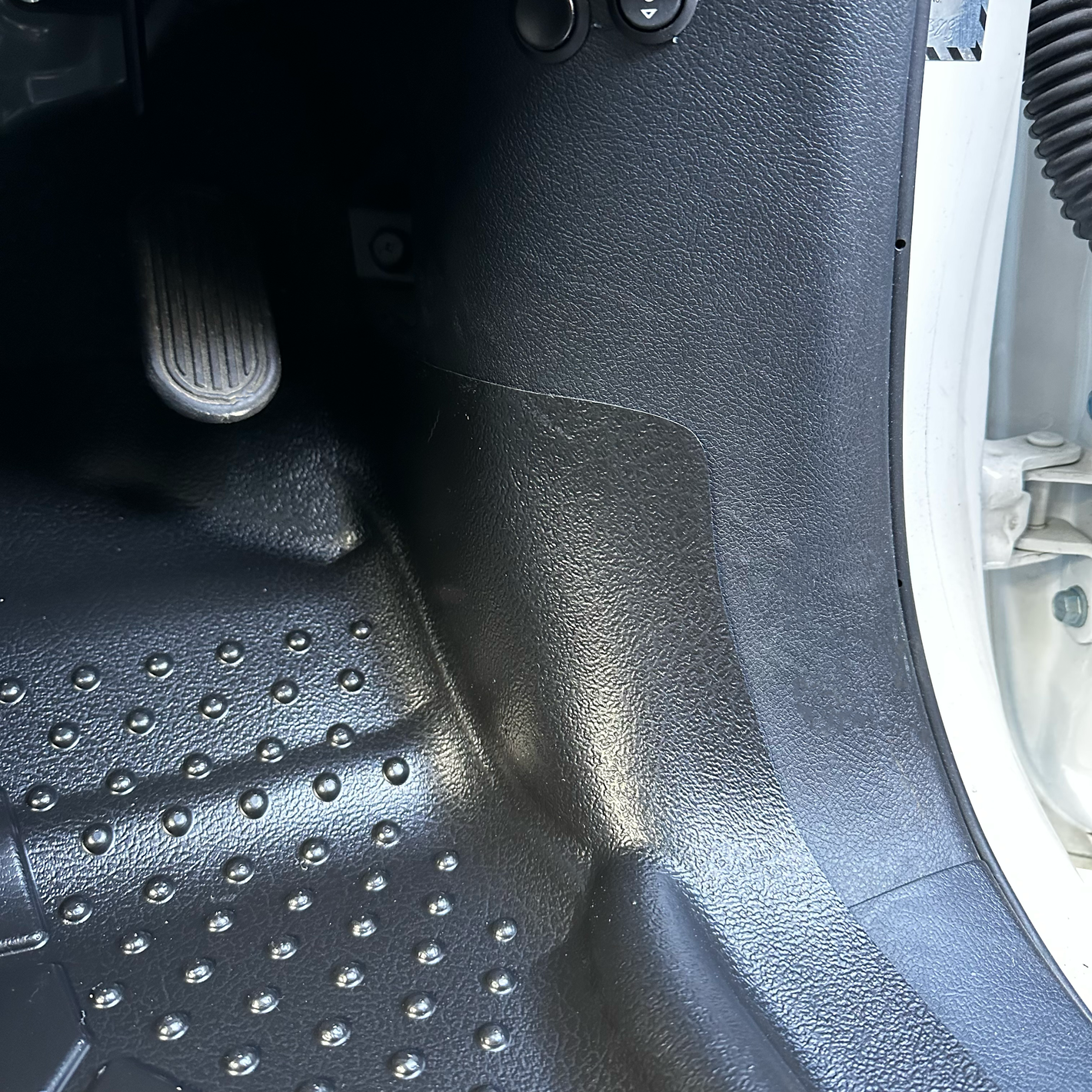 A close up of a MUDTAMER mat installed in a vehicle, showing the coverage on the vehicle's "A" pillar