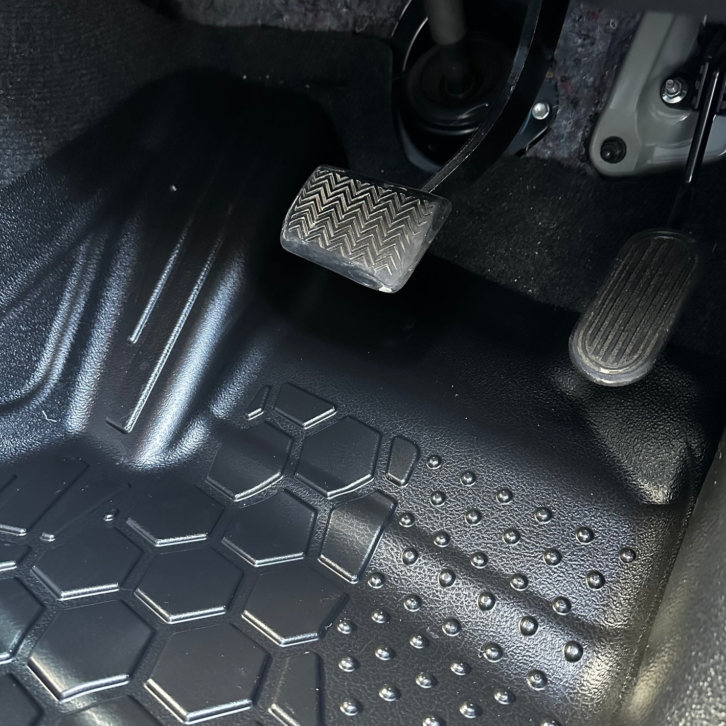 Close up of a MUDTAMER mat installed in a vehicle showing it in the footwell