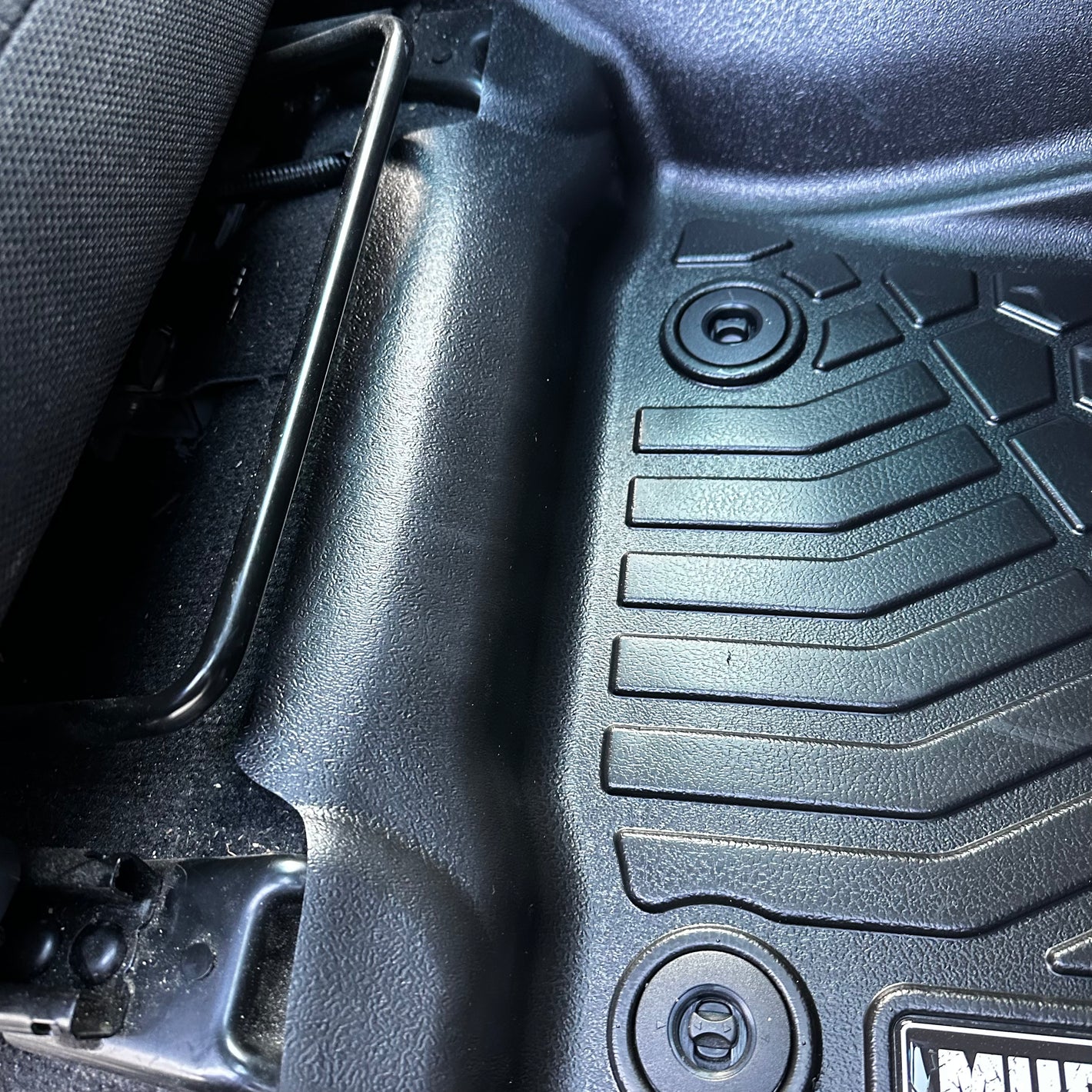 A close up of a MUDTAMER mat installed in a vehicle, focusing on the rear of the mat