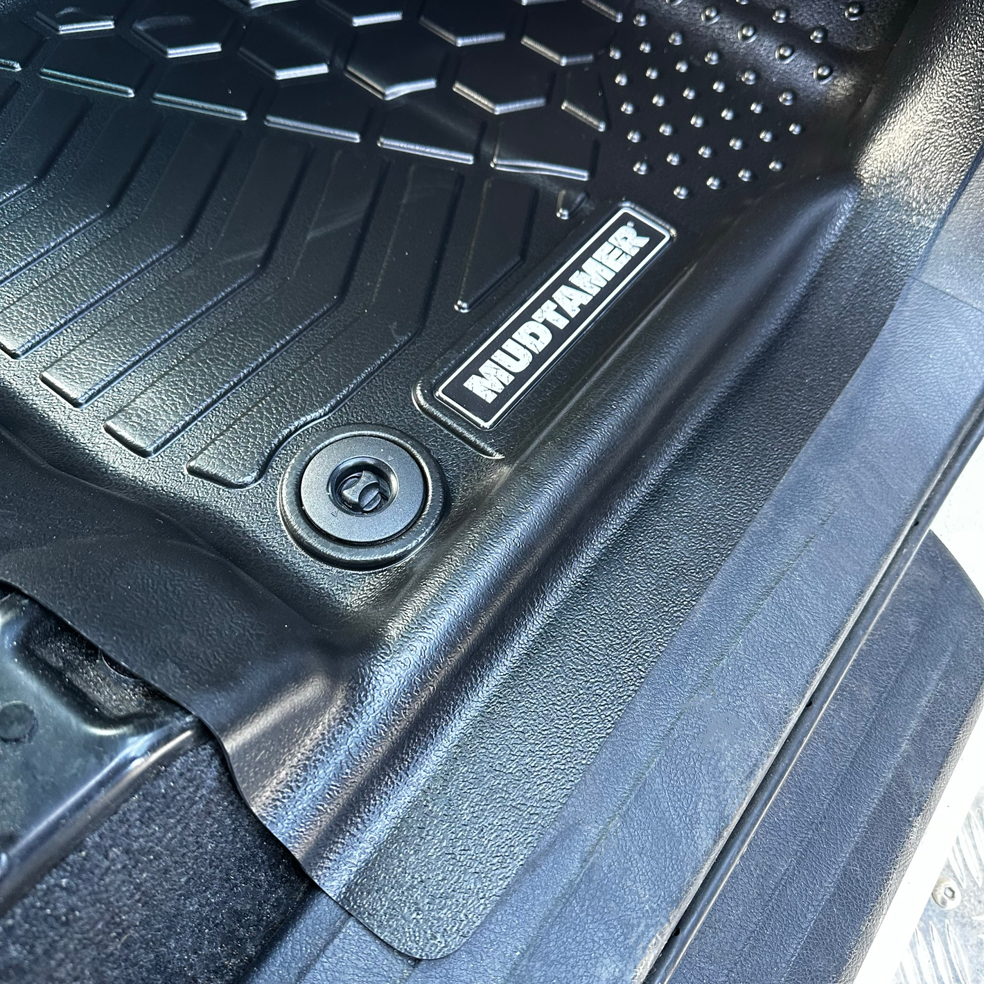 Close up of the MUDTAMER mat installed in a vehicle showing where it covers the door sill