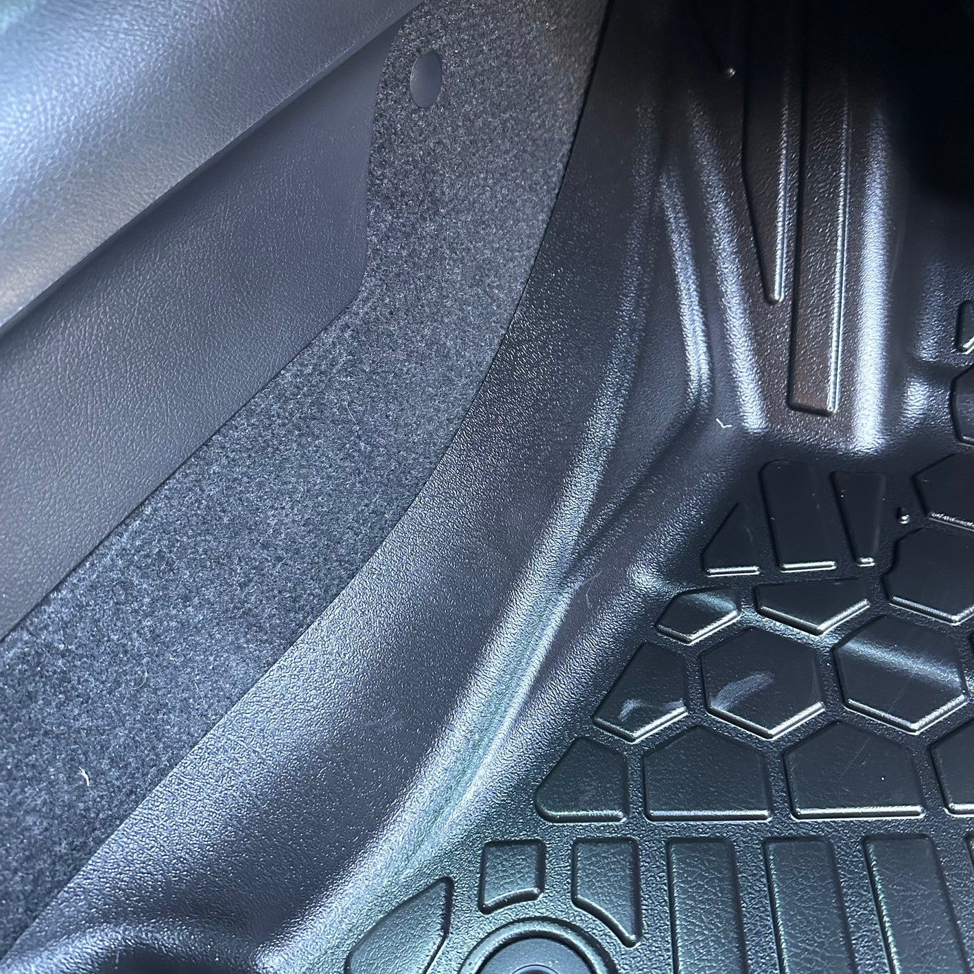 Close up of a MUDTAMER mat installed in a vehicle showing the transmission tunnel coverage
