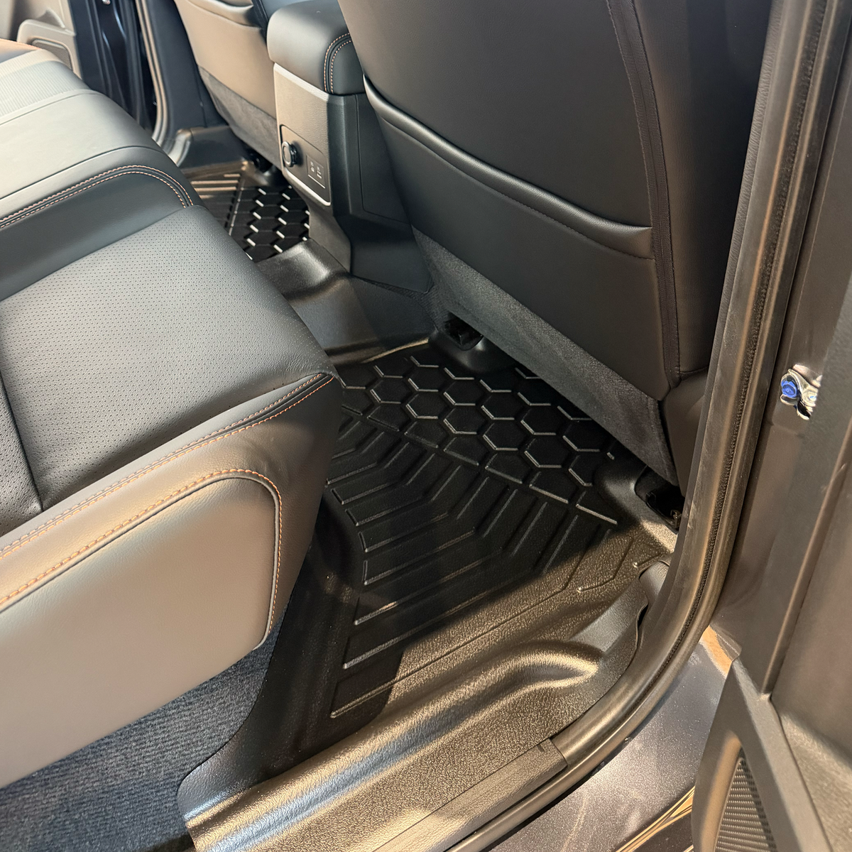 Black TPE floor mats installed in the rear of a vehicle, shown between grey seats.